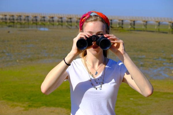 girl looking through binoculars while she is Birdwatching in Trinidad
