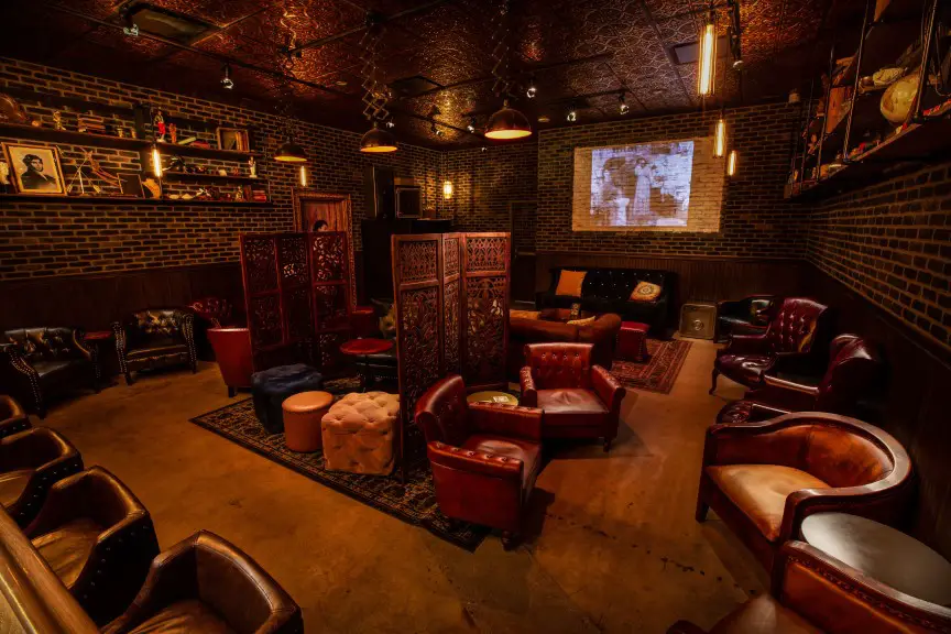 dim room with leather furniture and a tv diplayed on the brick wall