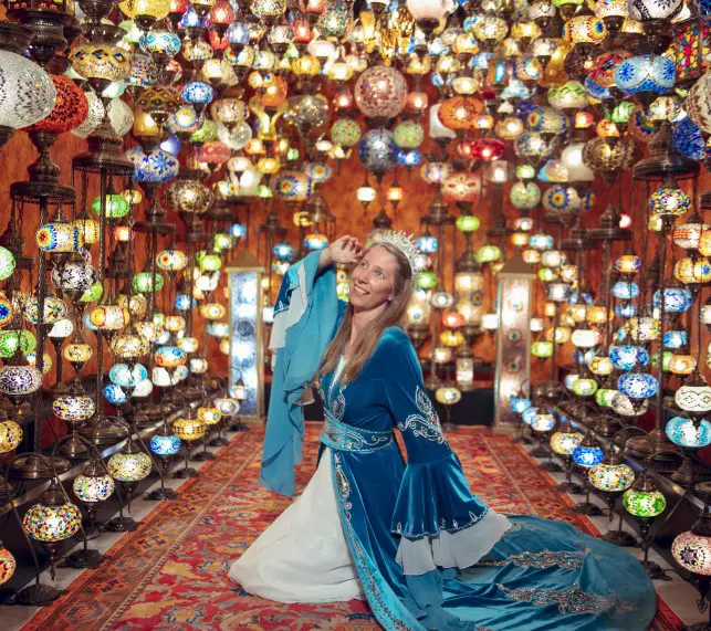 lady in a blue robe and crown in a room filled with Turkish Lamps at a photoshoot in Istanbul