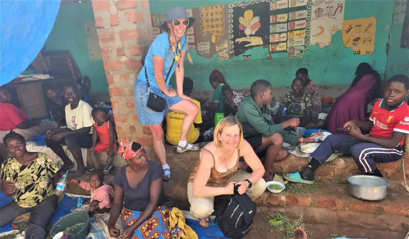 people sitting in the dirt in the kampala slum