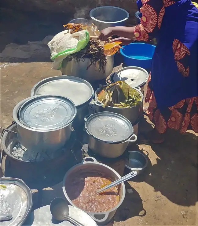 pots and pans with food in it on the ground in Kampala slum