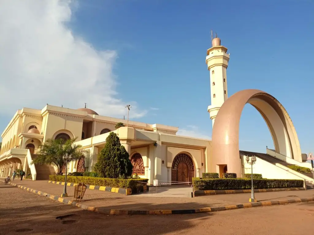 biege building with arch in front of it and minaret in background in the city of Kampala