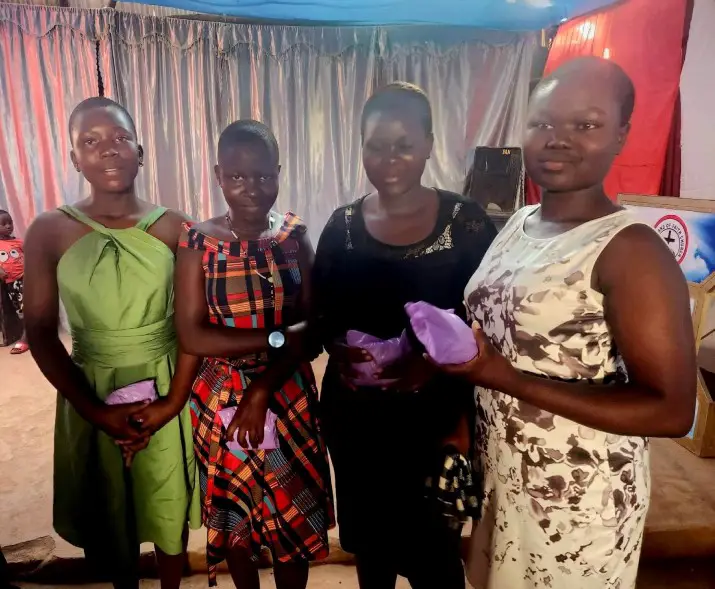 4 girls standing next to each other holding their sanitary pad donation