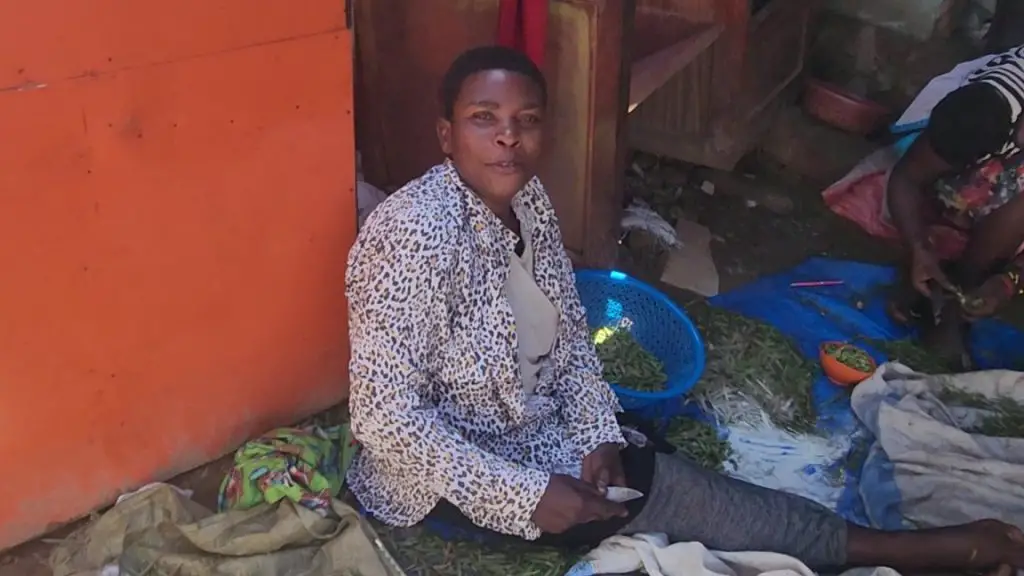 lady in a leopard print shirt sitting in the dirt in the kampala slum