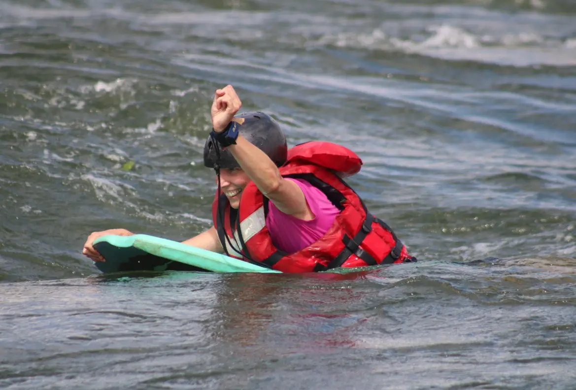lady on a small bodyboard in the rapids in the Nile River