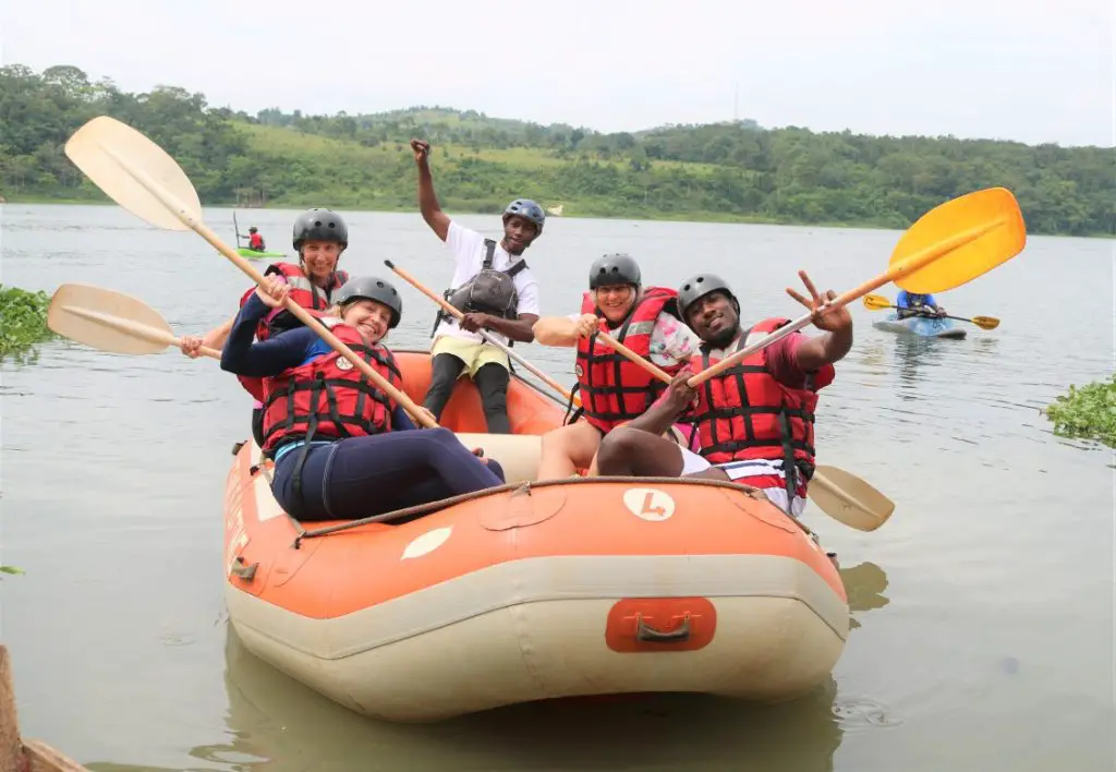 people with paddles up in the air in an orange raft, ready to go white water rafting in Uganda
