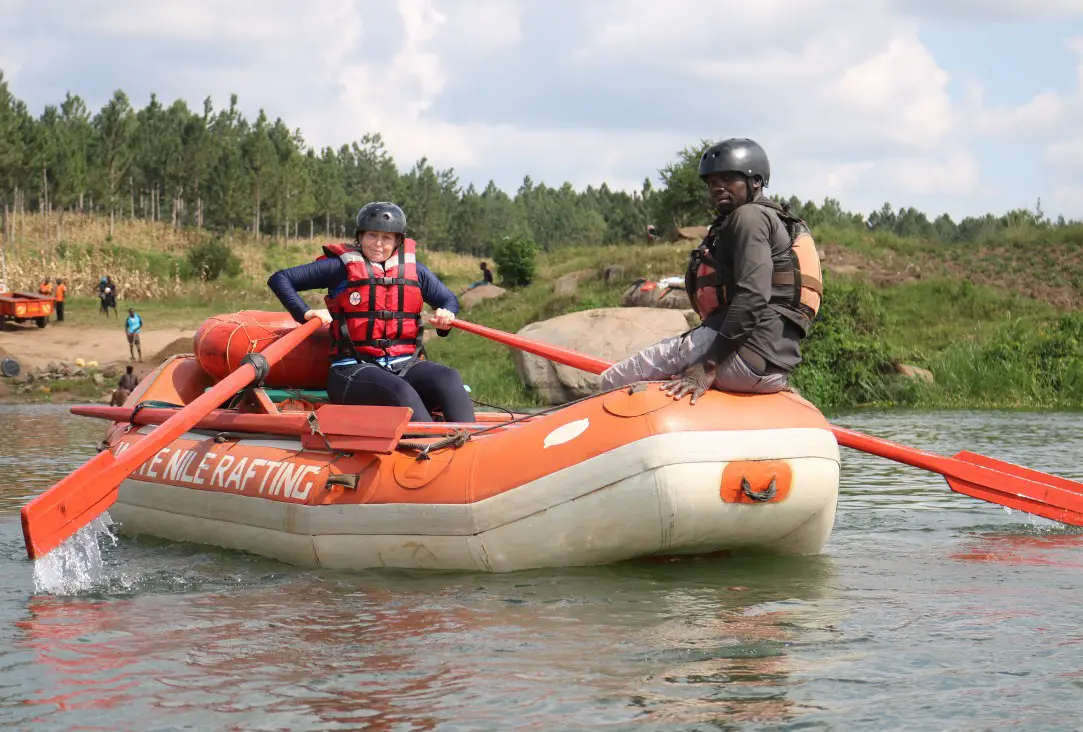 lady rowing the safety boat with guide watching on the white water rafting trip