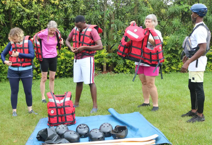 rafters putting on safety gear like life vests and helmets before white water rafting trip