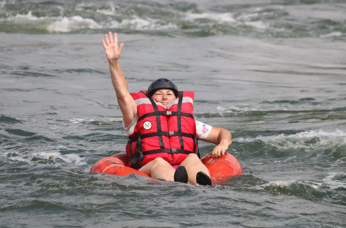 lady in an innertube on the Nile River with 1 hand raised in the air