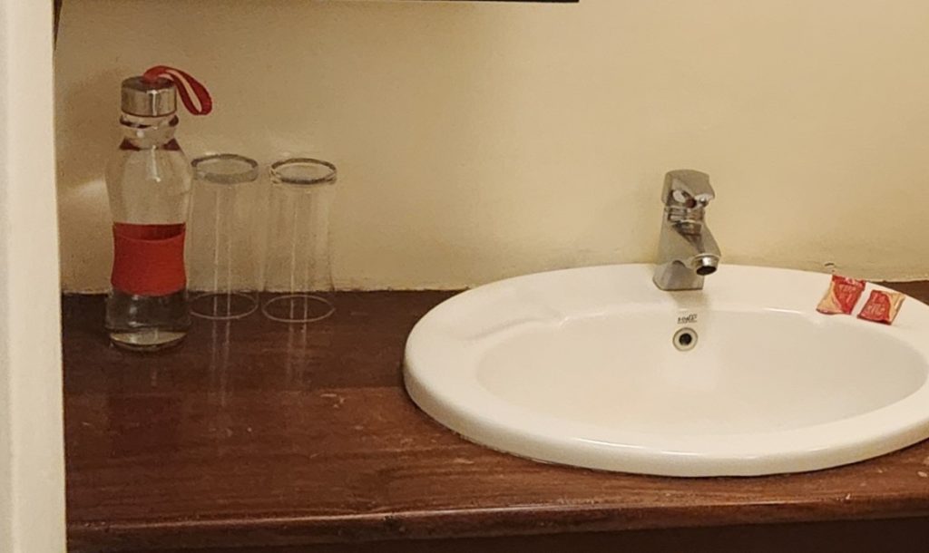 glass water on a sink - complimentary water provided by lodge in Uganda