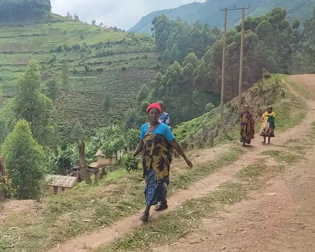 many people walking along the side of the dirt road in Uganda