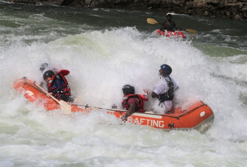 people in a raft boat  under a lot of water during white water rafting