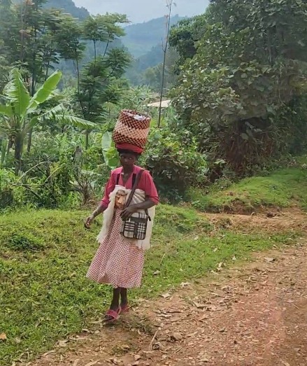 lady walking along the side of the road in Uganda with a basket on head
