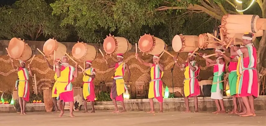 line of colorful drummers with instruments on their heads showing Native Uganda customs displayed by Nderer Troupe in Kampala