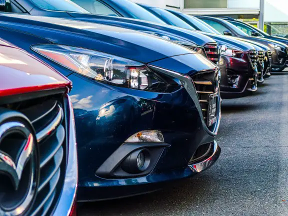 closeup of the front of several rental cars parked in a row