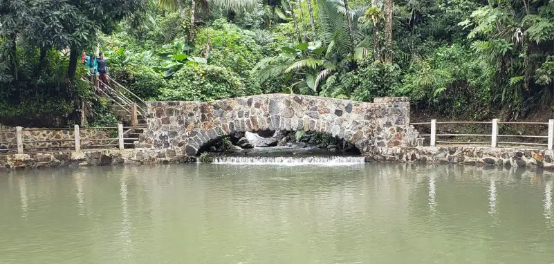stone bridge over water surrounded by green trees at Grand Bano one of the best instagrammable places in Puerto Rico