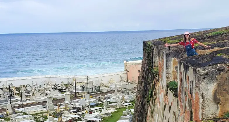 girl peaking out from the edge of a Historical Fort and Cemetary in San Juan Puerto Rico 