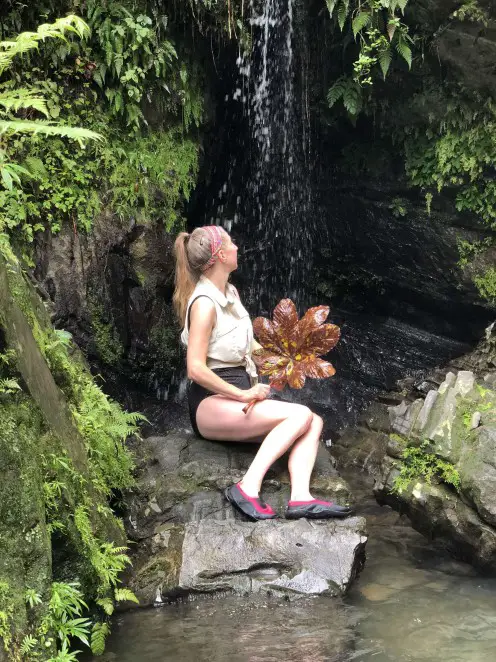 holding a leaf in front of Juan Diego Falls one of the best instagrammable places in Puerto Rico