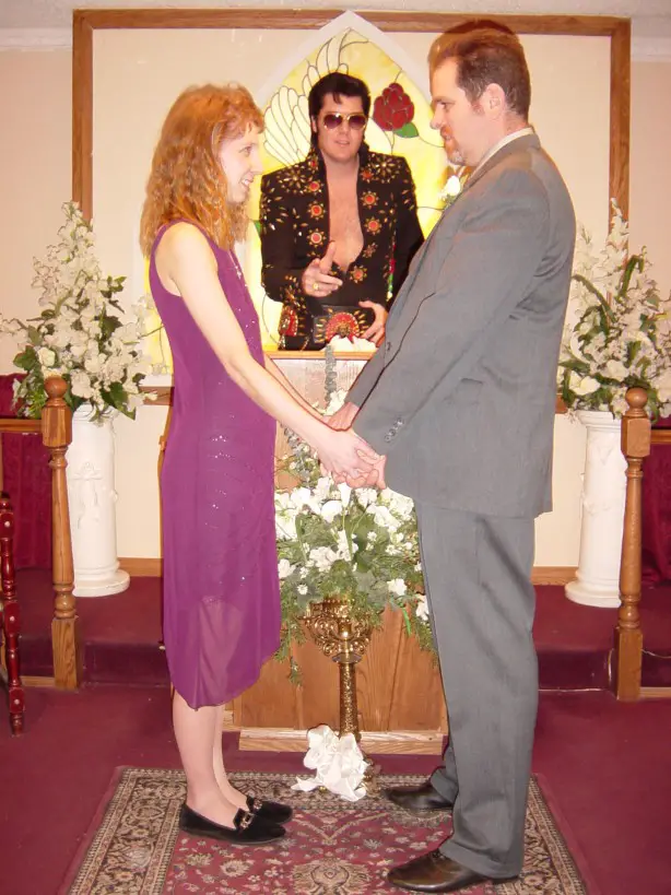 man and woman facing each other and  holding hands in front of an altar and Elvis