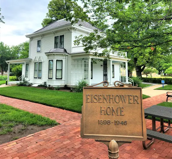 small white house with a plaque in front of it for Eisenhower Boyhood home in Abilene Kansas