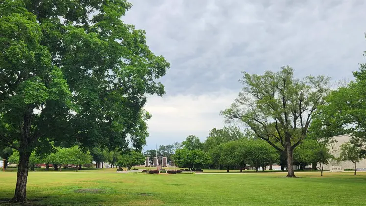 grassy area surrounded by trees and a statue in the distance at the Eisenhower Museum in Abilene Kansas