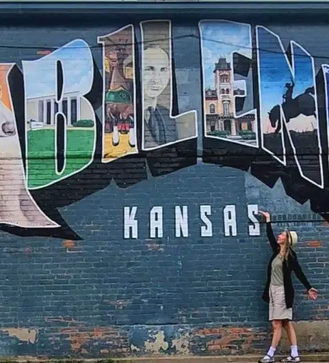 abiliene Kansas Mural with lady standing in front of the wall pointing at it