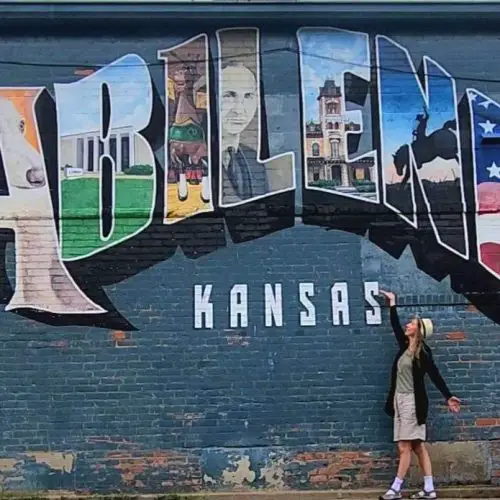 abiliene Kansas Mural with lady standing in front of the wall pointing at it