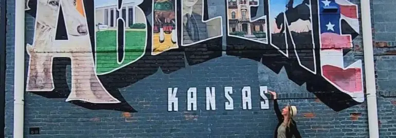 abiliene Kansas Mural with lady standing in front of the wall pointing at it
