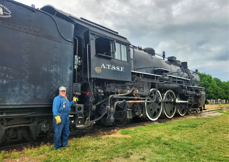 train engineer standing on the side of a locomotive engine at Abilene Smoky Valley Railroad in Kansad