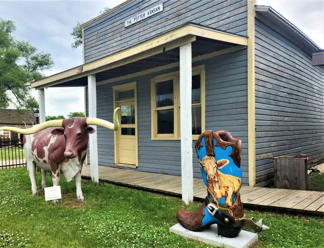 cowboy boot with a cow on it along side a longhorn statue in front of an old building in old town in Abilene Kansas