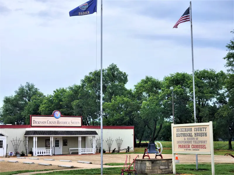 white building with flags in front of it at the Dickinson County Heritage Center