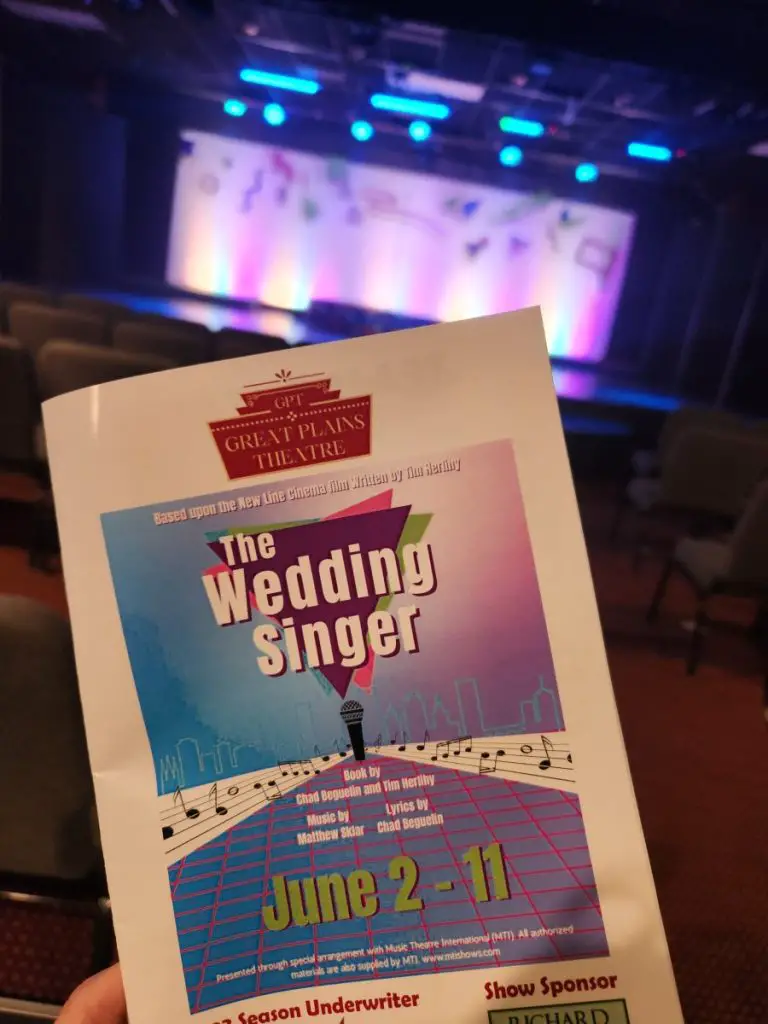 the Wedding Singer program book in front of the glowing stage at Great Plains Theatre in Abilene Kansas