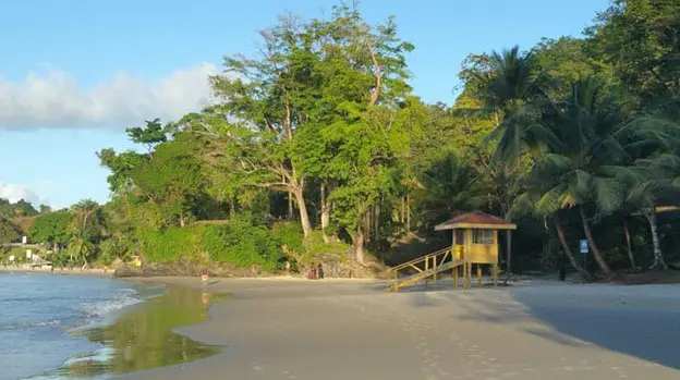 little yellow hut on the beach with trees in the backgroundat Las Cuevas Beach in Trinidad