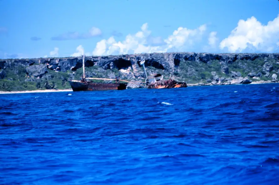 shipwreck in the blue water with a beach in the distnace