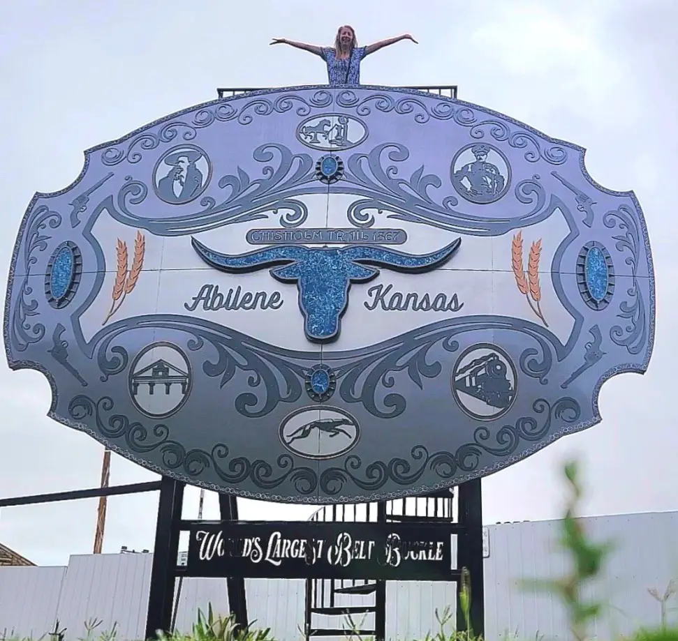 lady standing at the top of a very large belt buckle roadside attraction in Abilene Kansas
