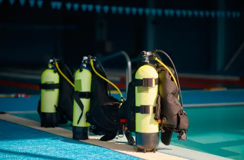 3 scuba diving oxygen tanks next to a pool