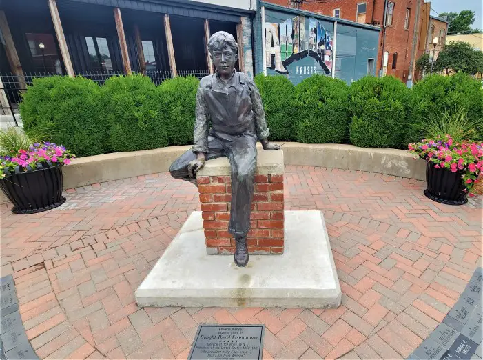 young boy statue of Eisenhower in front of green shrubs at Little Ike Park in Abilene Kansas