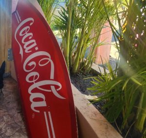 red coca cola surfboard in front of some green plants in Puerto Rico