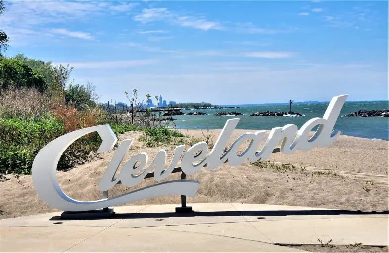 script Cleveland sign on a beach in front of downtown Cleveland buildings