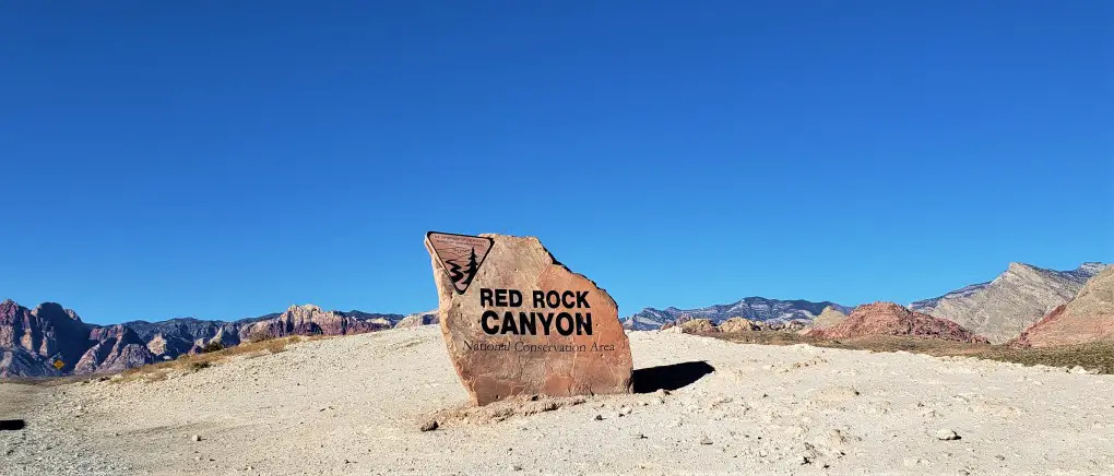 red stone Red Rock Canyon Entrance sign with red rock mountains in the background