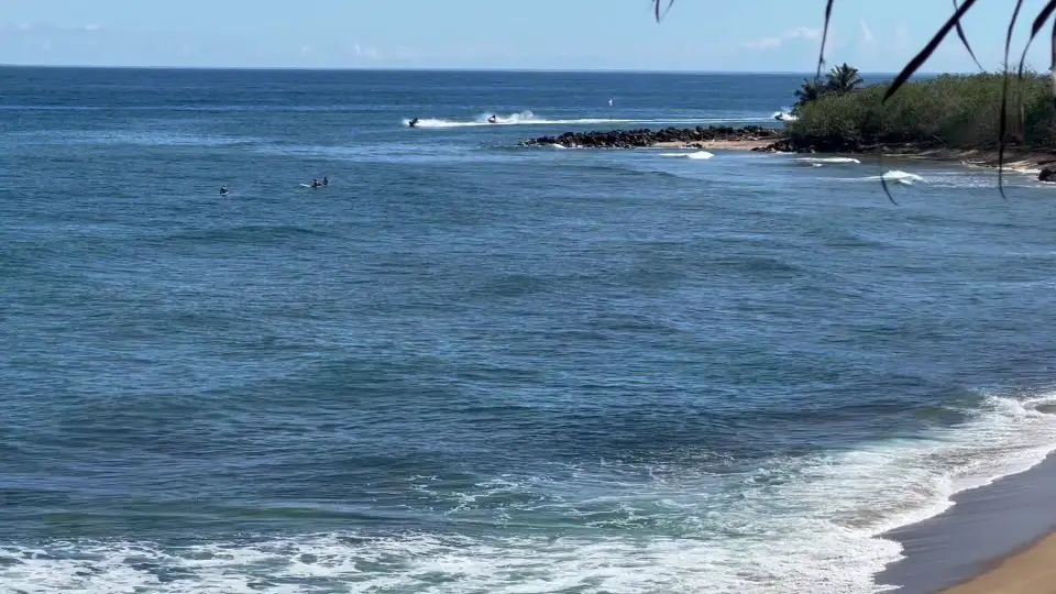 3 surfers and jet skiers in the water riding the small waves