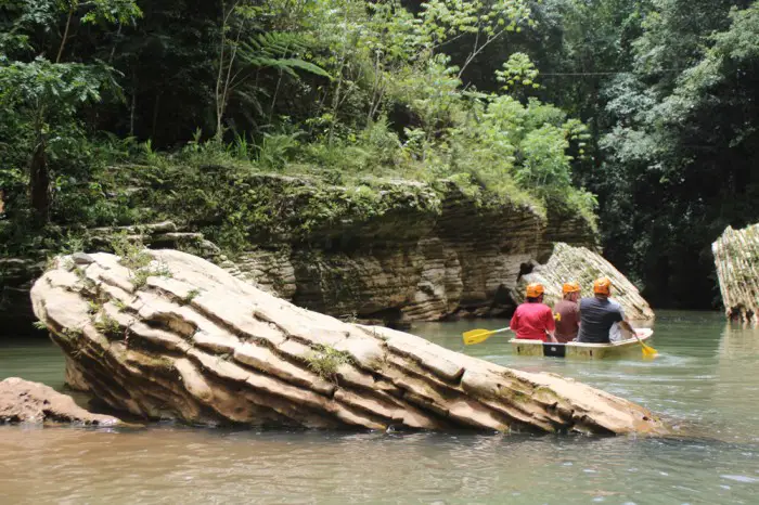 boat with 3 people paddling in the river