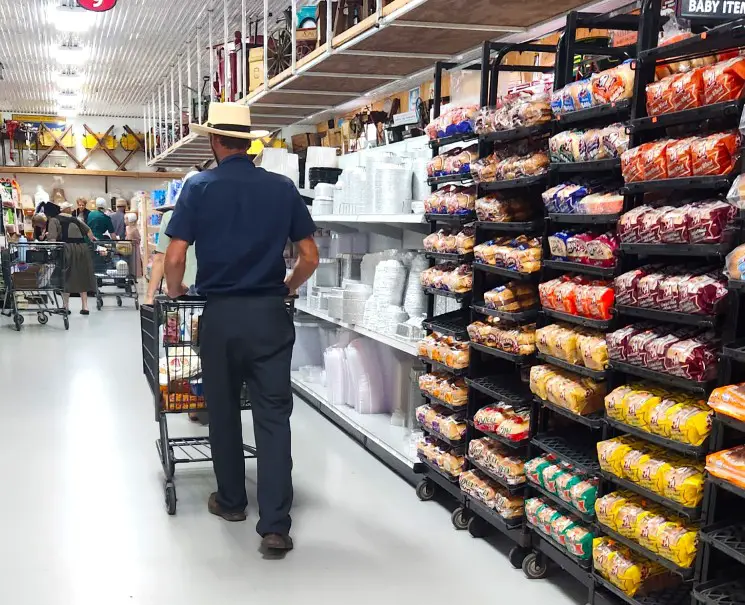 Amish man in a hat pushing a grocery cart down the bread aisle at the bulk food store in Shipshewana