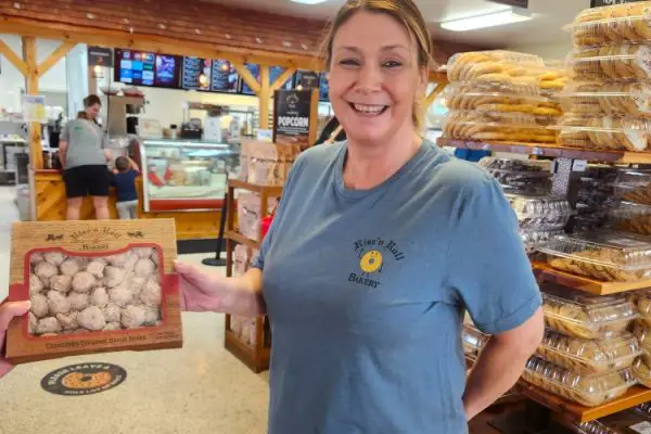 lady holding up a box of Donuts at Rise and Roll Bakery in Shipshewana