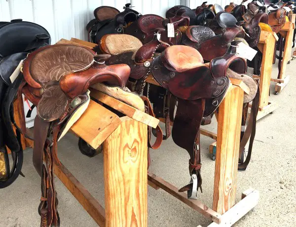 many horse saddles on a wooden display in Shipshewana Indiana