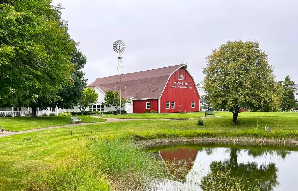 Red barn Meno Hof Amish Museum in front of a lake reflecting the images in Shipshewana