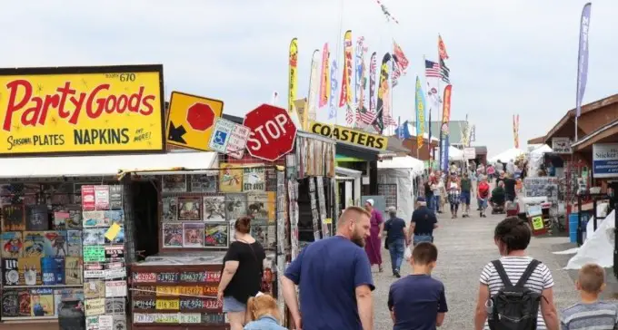 people walking down an aisle of booths at the shipshewana flea market