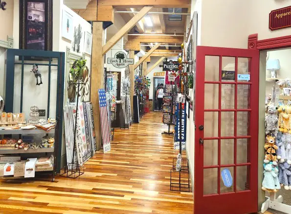 shops in a Shipshewana shopping mall with art and clothes on display in a hallway with a wooden floor