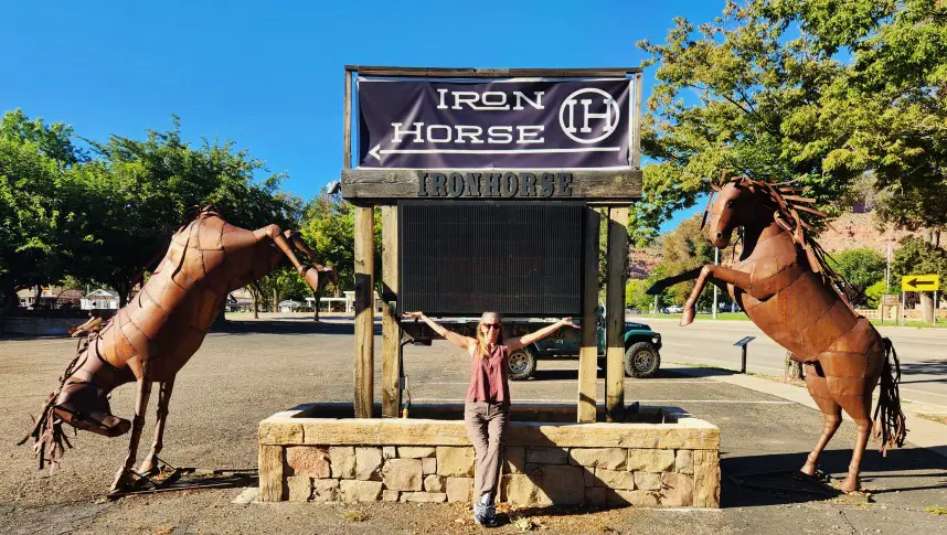 Iron Horse Restaurant sign with lady sitting with hands raised and two horse statues on each side