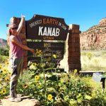 lady standing with arms spread by a Kanab Utah sign